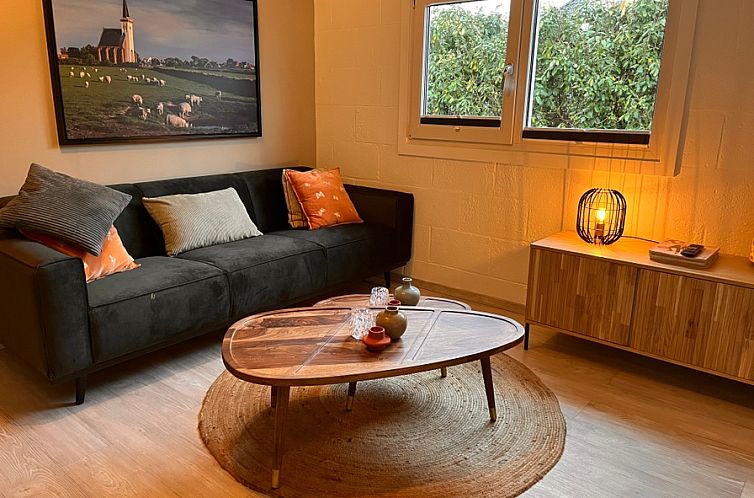 Cozy living room in vacation home Oostenwind, De Cocksdorp, Texel with comfortable sofa and atmospheric lighting.