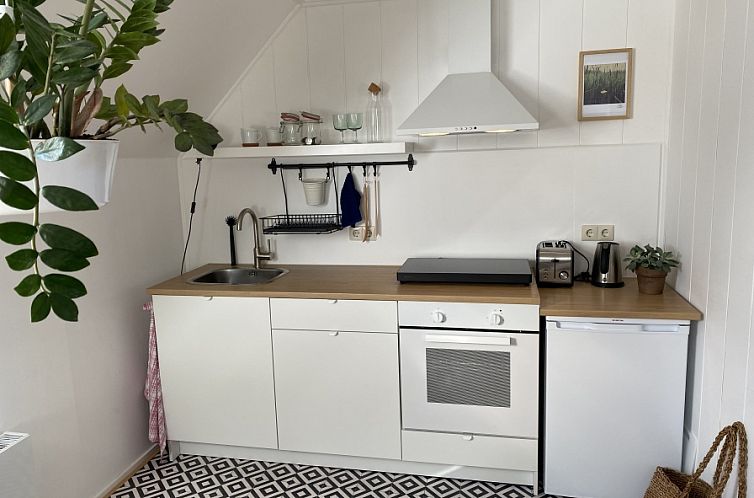 Modern kitchenette in Double studio 4, Den Hoorn, Texel, with sleek white cabinets and wooden worktop.