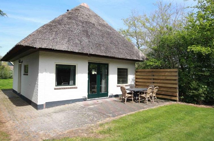 Cozy vacation home Nieuwlanderweg 69 with thatched roof in De Koog, Texel, surrounded by greenery and a spacious terrace.