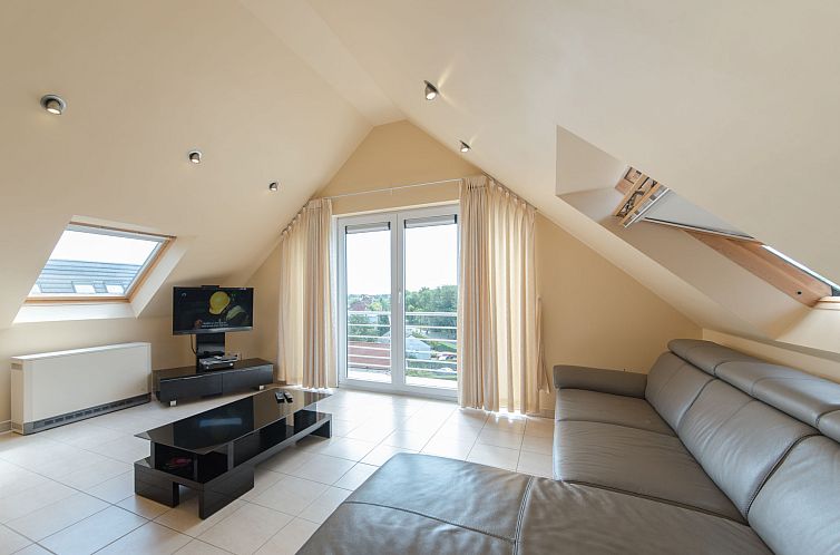 Helles Wohnzimmer des Apartments Goldsands II 402 im obersten Stockwerk in De Haan, Westflandern, mit moderner Einrichtung und Balkon.