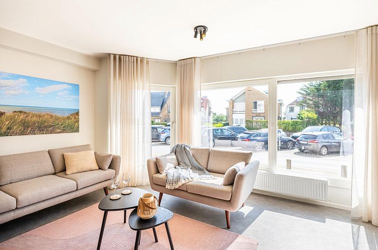 Bright living room of Iris ground floor vacation home in Koksijde, West Flanders, with comfortable sofas and views of the quiet street.