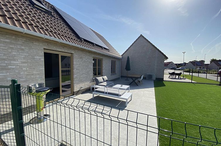 Geniessen Sie die sonnige Terrasse des Ferienhauses Westhinder I H71 in Koksijde, Westflandern, mit moderner Sitzecke und gruener Umgebung.