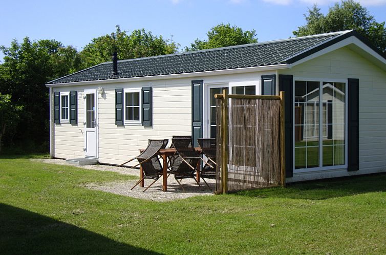 Vakantiepark De Koorn-aar Type E terras in De Dennen Texel, met houten tafel en stoelen in groene omgeving.
