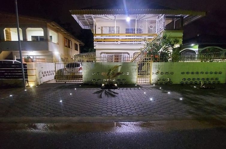 Nachtelijke aanblik van Fresh, een vakantiehuis in Paramaribo, Suriname, met moderne verlichting en omheinde tuin.
