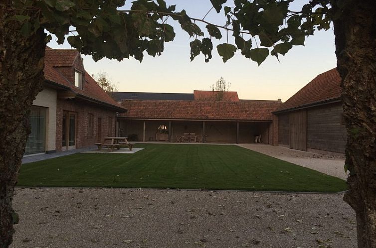 Rustikaler Innenhof des Ferienhauses Kortweunste in Merkem, Westflandern, umgeben von viel Gruen und ruhiger Natur.
