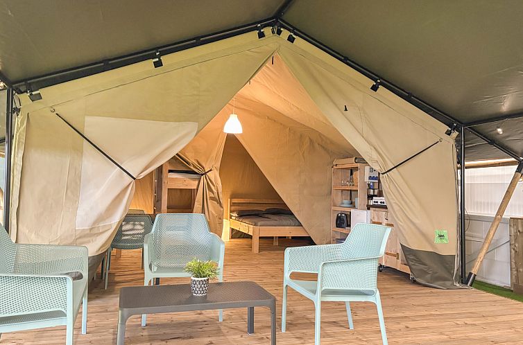 Entdecken Sie die einladende Safari-Zelt-Glamping-Lodge in Farso, Nordjuetland, Daenemark, mit einer grosszuegigen Terrasse und einem gemuetlichen Innenbereich.