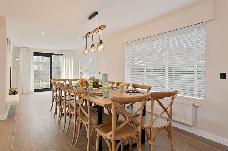 Speisesaal der Villa Miro, Ferienhaus in Sint-Idesbald, mit hellem Dekor und Holztisch.