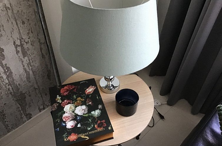 Stilvolle Ecke mit Tischlampe und Buch in der Wohnung von Residence Magnolia in Westende, Belgien.