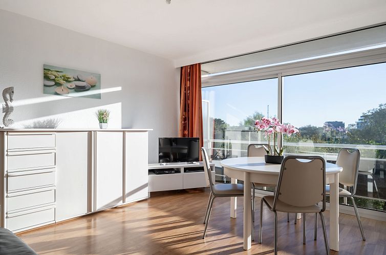 Helles Wohnzimmer der Ferienwohnung Residentie Astrid in Bredene, Westflandern, mit Blick auf den Garten und moderner Moeblierung.