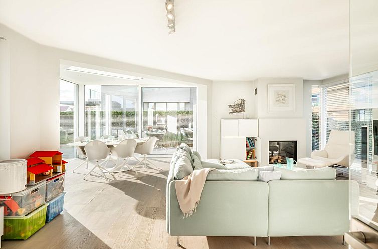 Helles Wohnzimmer des Ferienhauses La Perle in Oostduinkerke, Westflandern, mit moderner Einrichtung und Blick auf die Terrasse.