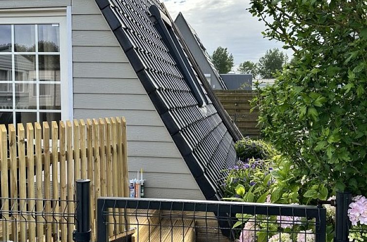 Chalet chez Dune in Oostduinkerke, a charming vacation home with wooden fence and flowering garden in West Flanders, Belgium.
