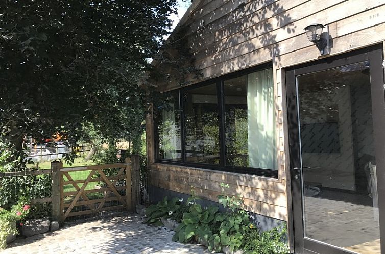 Bvba Kitty vakantiehuis in Lokeren, Oost-Vlaanderen, met een rustieke houten gevel en groene tuinomgeving.