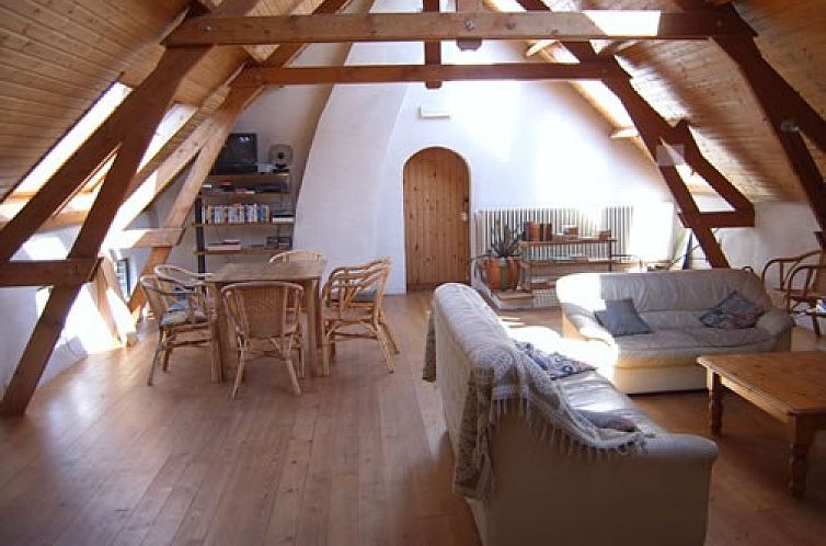 Geraeumiges Wohnzimmer mit Holzbalken im Ferienhaus Bosgat, Maarkedal, Ostflandern. Gemuetlicher Innenraum mit Sitz- und Essecke.