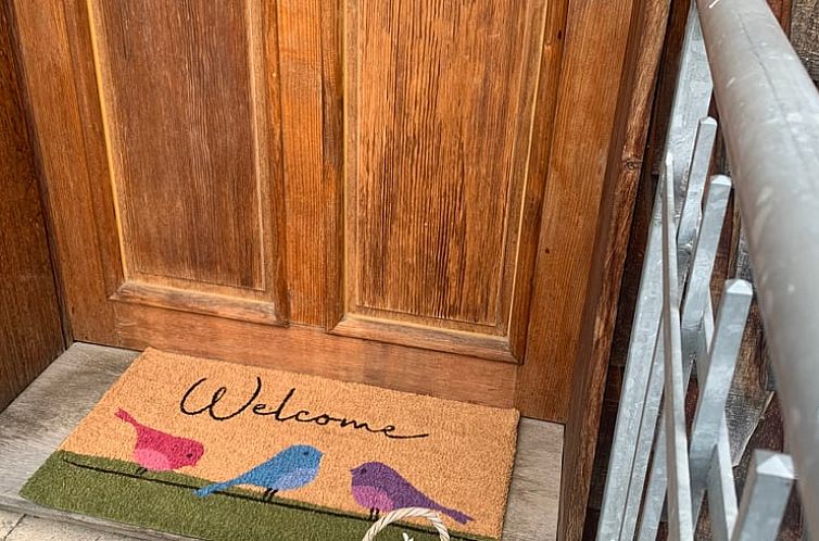 Ingang van Vakantiehuisje in Jesberg, Hessen. Gezellige deurmat met kleurrijke vogels in deze Duitse vakantiewoning.