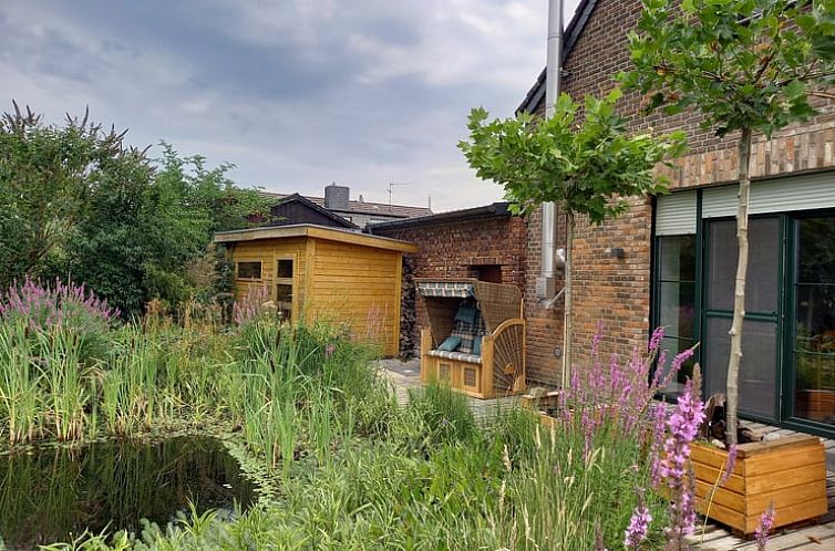 Rustiek vakantiehuisje in Neukirchen Vluyn omgeven door weelderige natuur en vijver in Noordrijn-Westfalen, Duitsland.