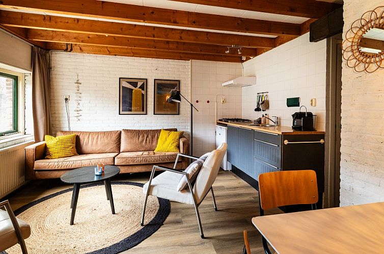 Gezellige woonkamer in Haas 2 appartement, Hoorn, Terschelling met houten balken en comfortabele zithoek.