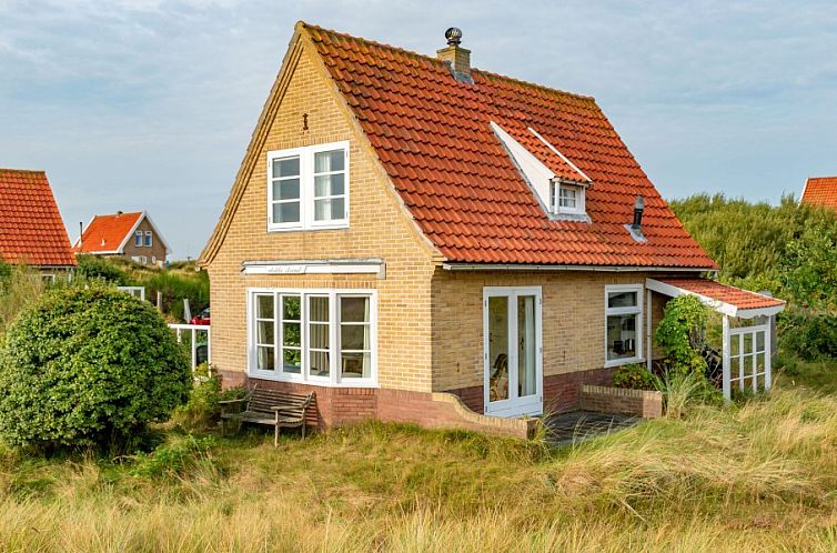 Vlakke Strand vakantiehuis in Midsland aan Zee, Terschelling met charmante gevel en rode dakpannen, omgeven door duinen.