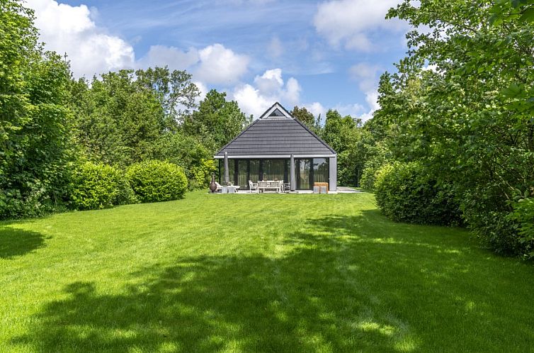 Noordhoek vakantiehuis in Midsland Noord, Terschelling omgeven door weelderige natuur en groene tuin, ideale plek voor ontspanning.