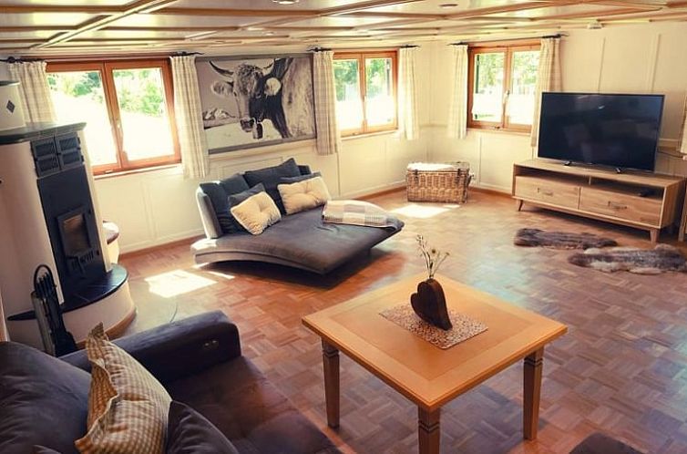 Innenbereich des Ferienhauses in Oberstaufen, Deutschland, mit geraeumiger Sitzecke und warmen Moebeln.