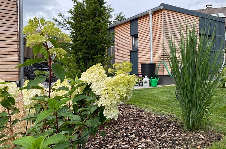 Ferienhaus Cottage in Schoenwald, Bayern, umgeben von ueppiger Natur und bluehenden Pflanzen fuer einen erholsamen Urlaub.