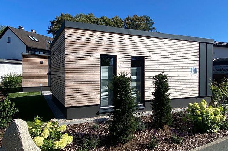 Modern vacation apartment in Schonwald, Bavaria surrounded by greenery and blue sky.
