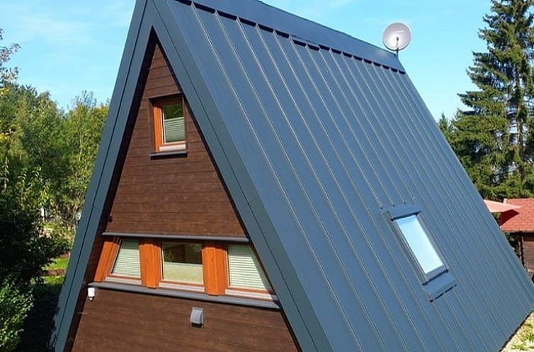 Geniessen Sie das Ferienhaus in Freyung, eine attraktive Unterkunft in Bayern, Deutschland, mit einem charakteristischen Spitzdach und umgeben von Gruen.