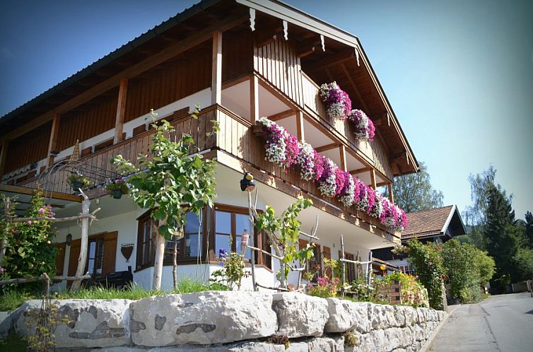 Ferienhaus Haus Sonnbichl in Schliersee, Bayern, umgeben von bunten Blumenkaesten und ruhiger Natur.