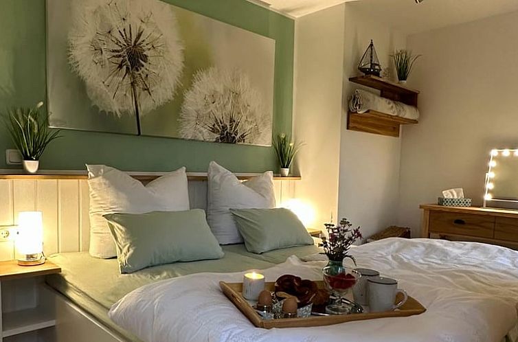 Rustikales Schlafzimmer des Ferienhauses in Trautskirchen, Bayern, Deutschland, mit sanfter Beleuchtung und einladendem Bett fuer eine gute Nachtruhe.