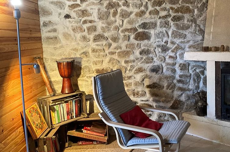 Rustic interior of Cottage in Saint Gervais d'Auvergne, vacation home in Auvergne, France with bookshelves and stone wall.
