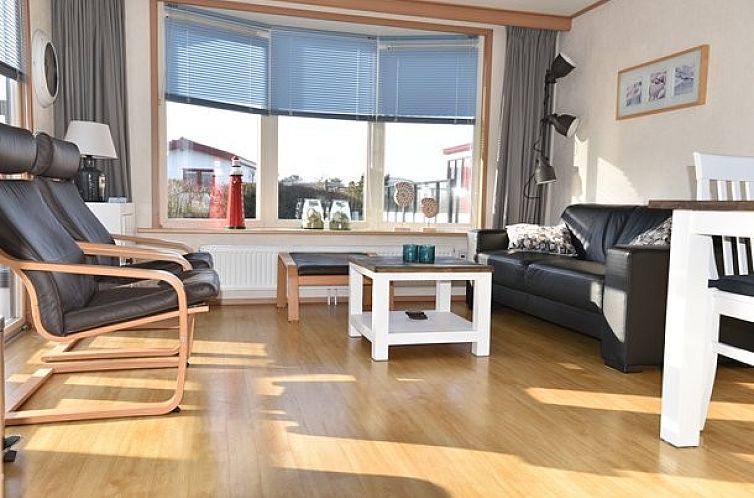 Cozy living room in Oester 167 chalet, Ballum, Ameland with lots of natural light and comfortable seating.
