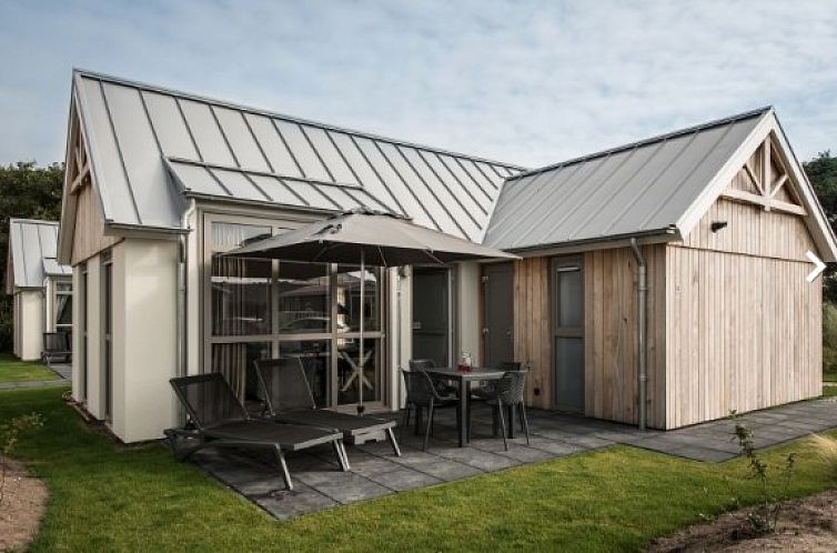 Exterior of VUURTORENLODGE 4, a vacation home in Hollum, Ameland with modern veranda and deck chairs.