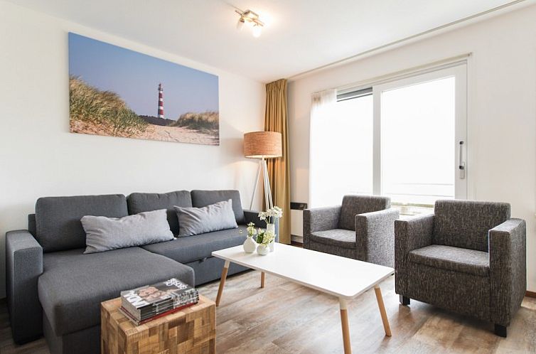 Gezellige woonkamer van appartement Wad in Hollum, Ameland met comfortabele banken en uitzicht op de Waddeneilanden.