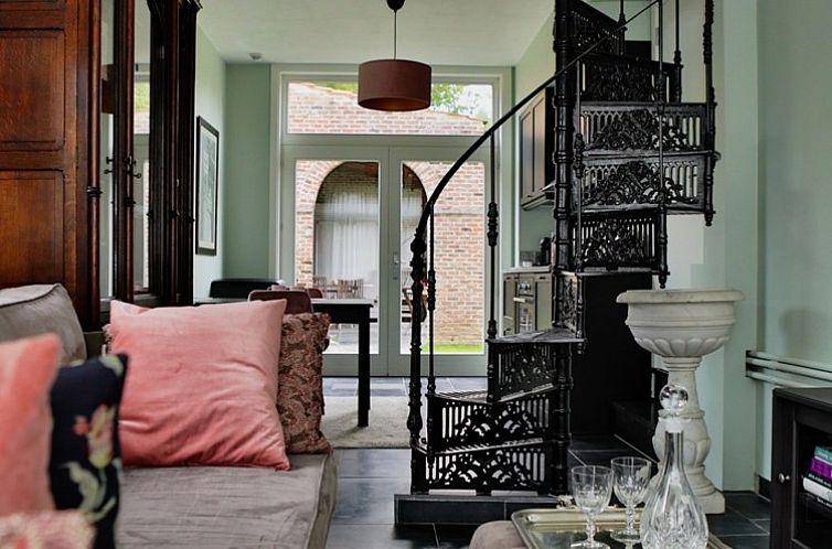 Gemuetliches Wohnzimmer im Ferienhaus Amand'eau, Sint-Amands, Antwerpen, mit verschnoerkelter Wendeltreppe und bequemer Sitzecke.