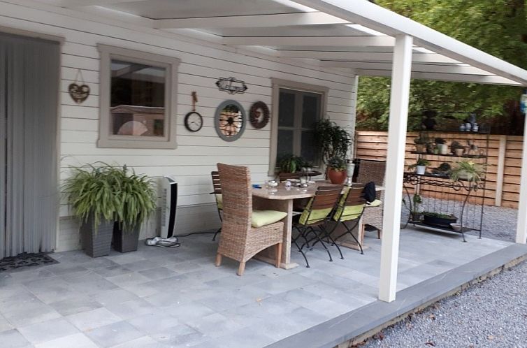 Veranda of Hertberg Lodge in Herselt, Antwerp, vacation home with cozy sitting area and green surroundings.