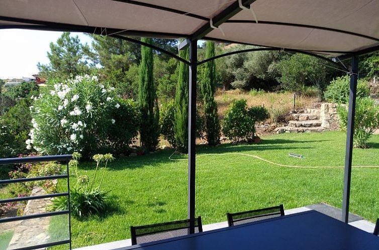 Ontspan op het terras van Solenzara vakantiehuis met uitzicht op de weelderige tuin in Corsica.