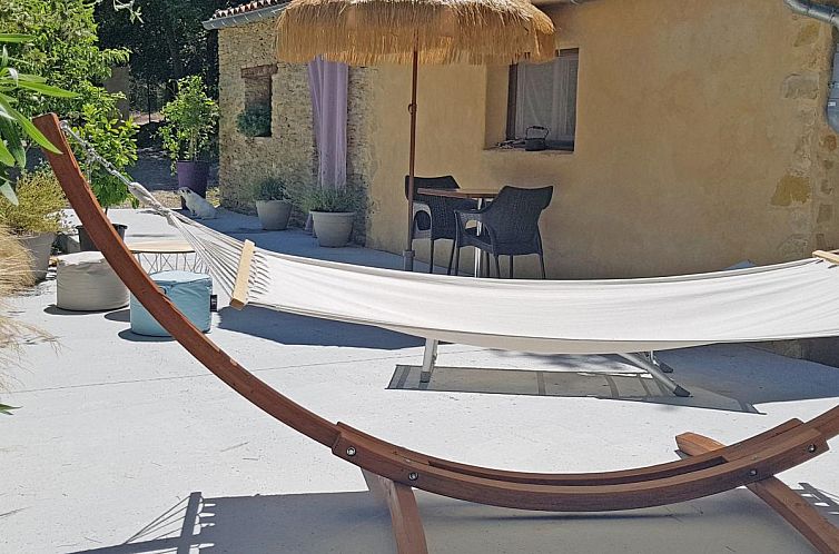Enjoy peace and quiet on the terrace of La petite Pinede in Faucon, Provence, with a comfortable hammock and inviting outdoor space.