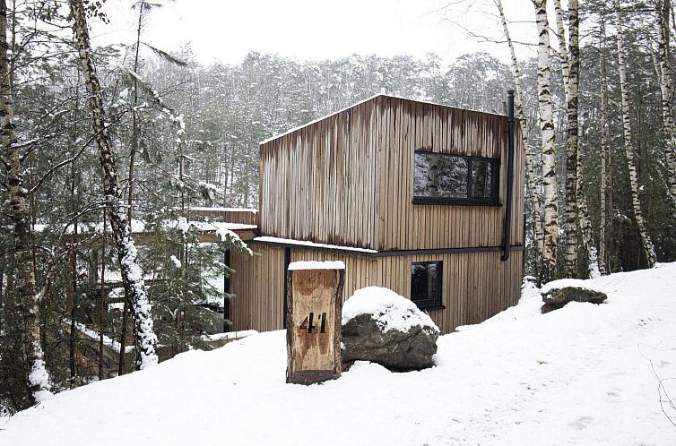 Comfort Sweet vakantiehuis met hottub in Neeroeteren, Limburg omgeven door groene natuur en rustieke houten architectuur.