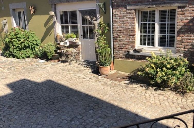 Charmante binnenplaats van vakantiehuis FreLune in Tongeren, Limburg, Belgie met rustieke stenen en groene accenten.