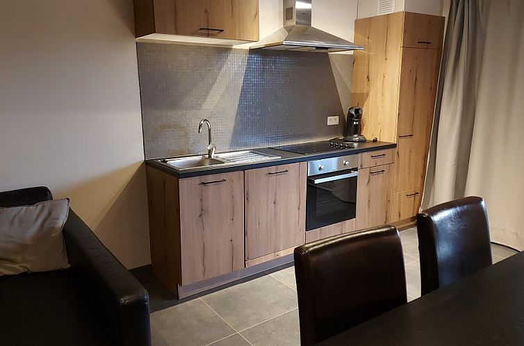 Moderne keuken in vakantiehuis D'hoef, Beringen-Beverlo, Limburg, Belgie, met houten kasten en comfortabele eetruimte.