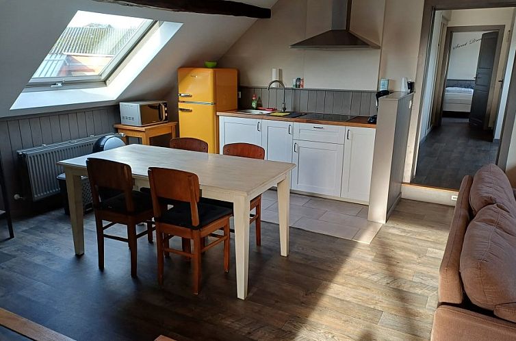 Cozy kitchen in Aan Maas & Grens vacation home in Kinrooi, Limburg, Belgium, with wooden table and retro fridge.