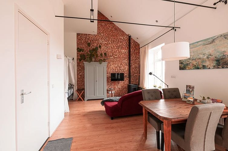 Gemuetliches Wohnzimmer eines Ferienhauses in St.-Pieters-Voeren, Limburg, Belgien, mit moderner Einrichtung und authentischer Backsteinwand.