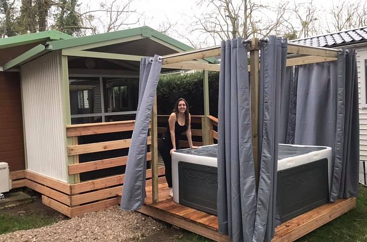 Ferienhaus "Chalet du Belier" in Frankreich, mit einem luxurioesen Whirlpool auf der Veranda, umgeben von viel Gruen.