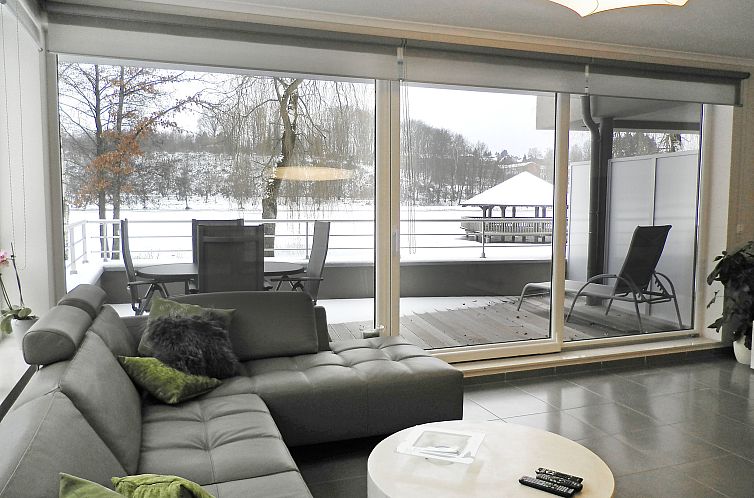 Cozy living room overlooking the snowy lake from Apartment Les Terrasses du Lac in Vielsalm, Ardennes, Belgium.