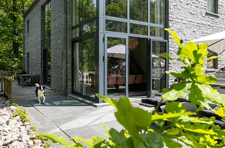 Veranda of La Roche Durbuy vacation home in Ardennes, Belgium with glass doors and green surroundings.