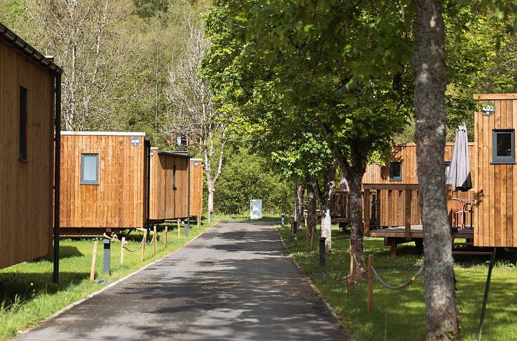 Ecolodge-Ferienhaus in Houffalize, Ardennen, Belgien mit einladender Terrasse, umgeben von ueppiger Natur.
