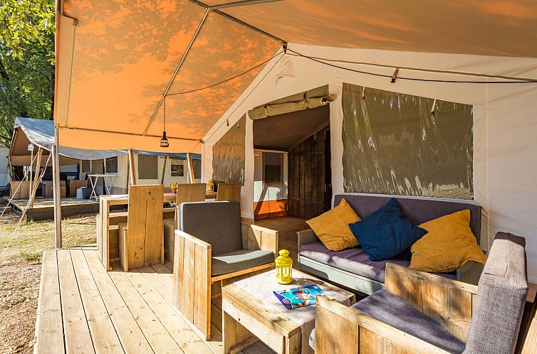 Die Terrasse von Safari Tent Luxe, einem Ferienhaus in Porec, Istrien, Kroatien, bietet Entspannung in der Natur mit Holzmoebeln und einem sonnigen Ambiente.