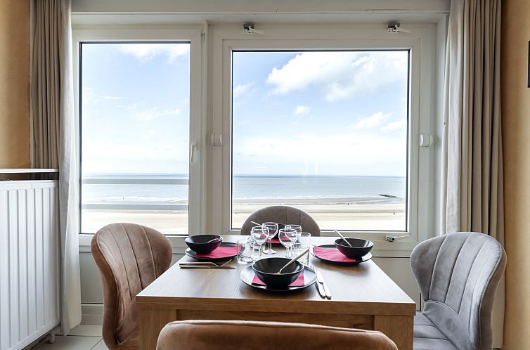 Enjoy the ocean view from Apartment Les Algues in Blankenberge, on the Belgian coast, with an elegant dining area by the window.