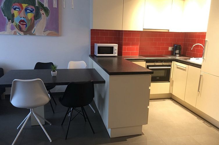 Modern kitchen in apartment Beethoven in Knokke on the Belgian coast, with stylish decor and red accents.