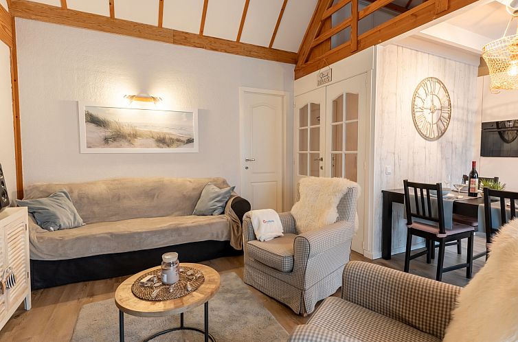 Gemuetliches Wohnzimmer des Ferienhauses Strandhuis in Bredene an der belgischen Kueste. Komfortable Sitzecke mit warmer Einrichtung und Essbereich.