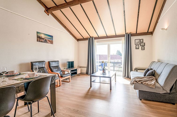 Lichte woonkamer van Appartement Zeewind II A 11 in Bredene, Belgische kust, met moderne inrichting en uitzicht op het terras.